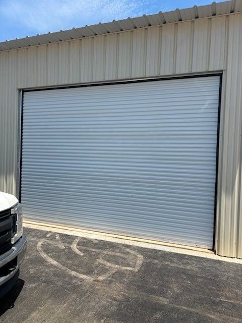 A white truck is parked in front of a white garage door.