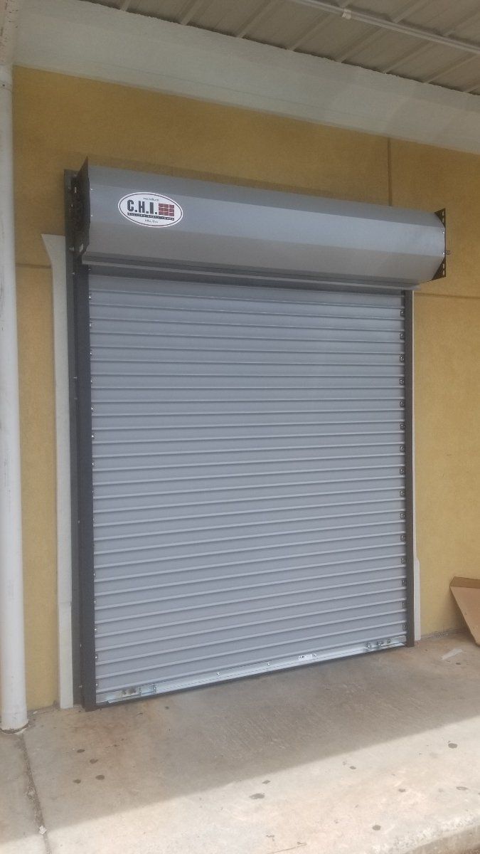 A gray garage door is sitting on the side of a building.