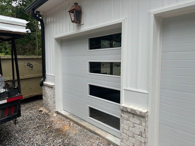 A white garage door with three windows and a golf cart parked in front of it.