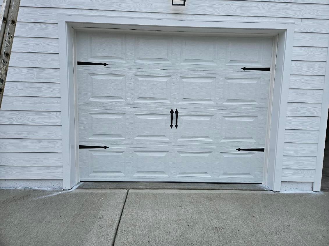 A white garage door with black hinges on a white building