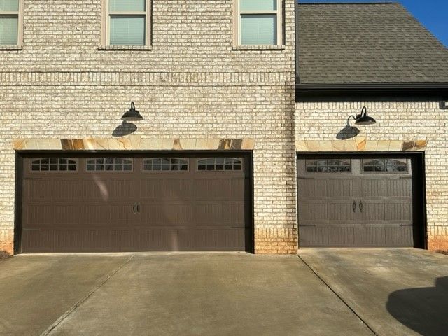 There are two garage doors on the side of a brick building.