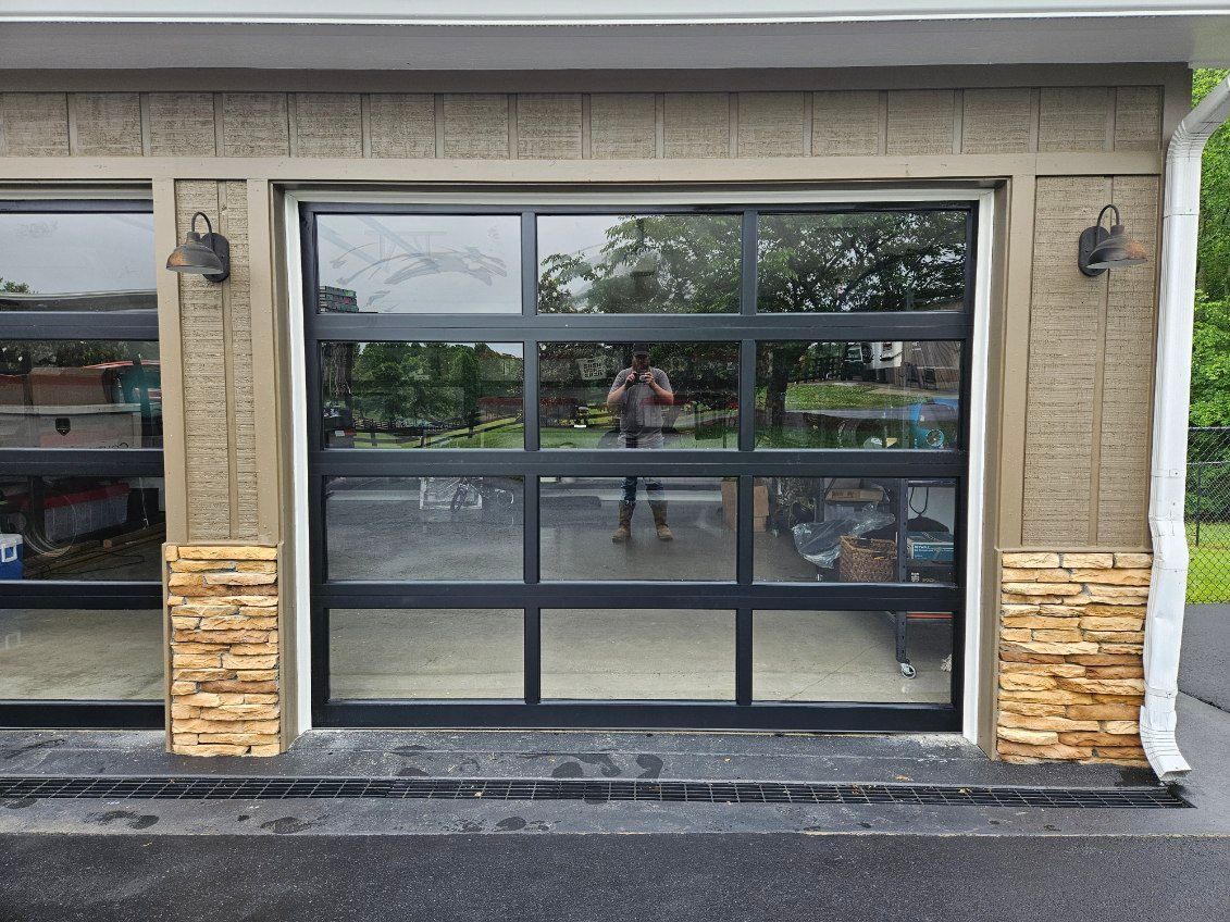 A garage door with a lot of windows and a reflection of trees in it.