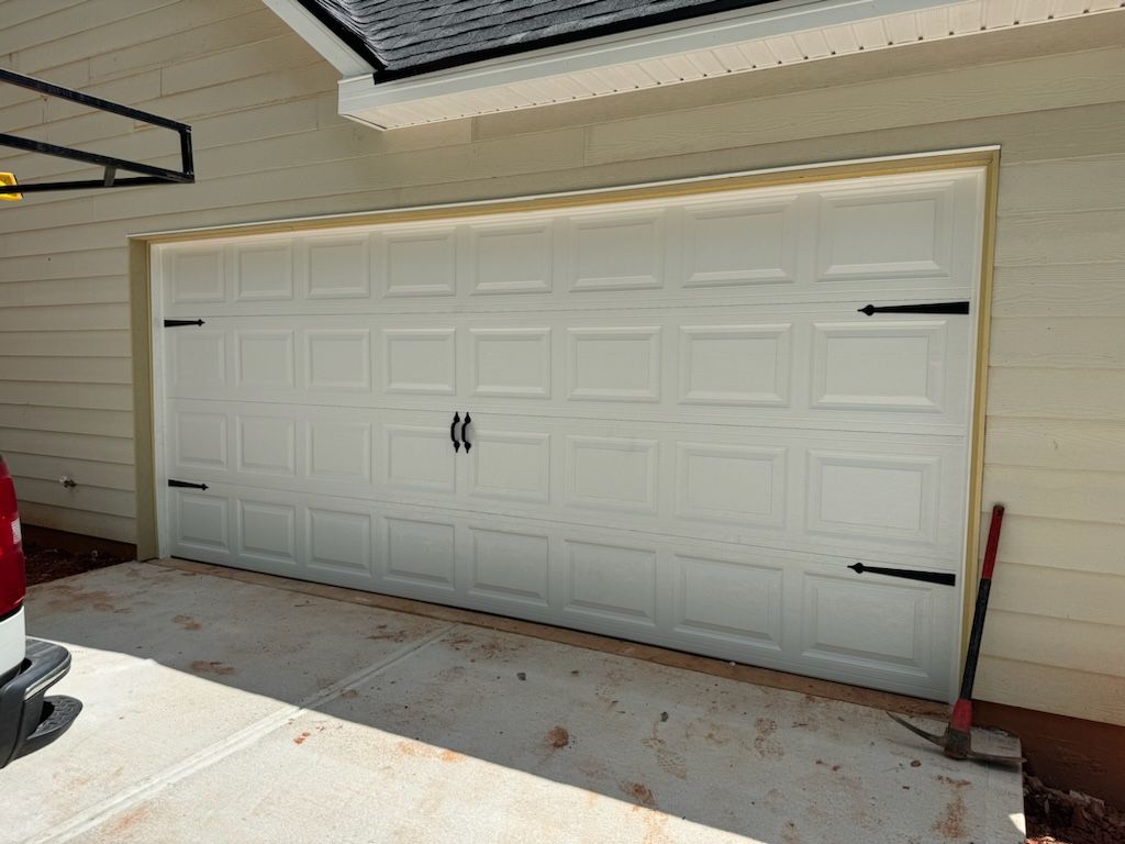 A white garage door is open and a red truck is parked in front of it.