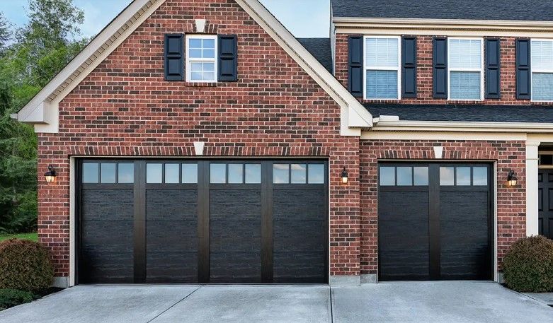 A brick house with black garage doors and black shutters