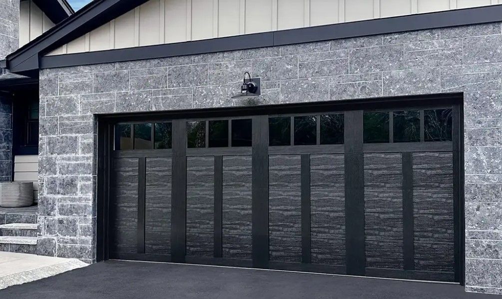 A black garage door is sitting in front of a brick house in Douglasville Ga.