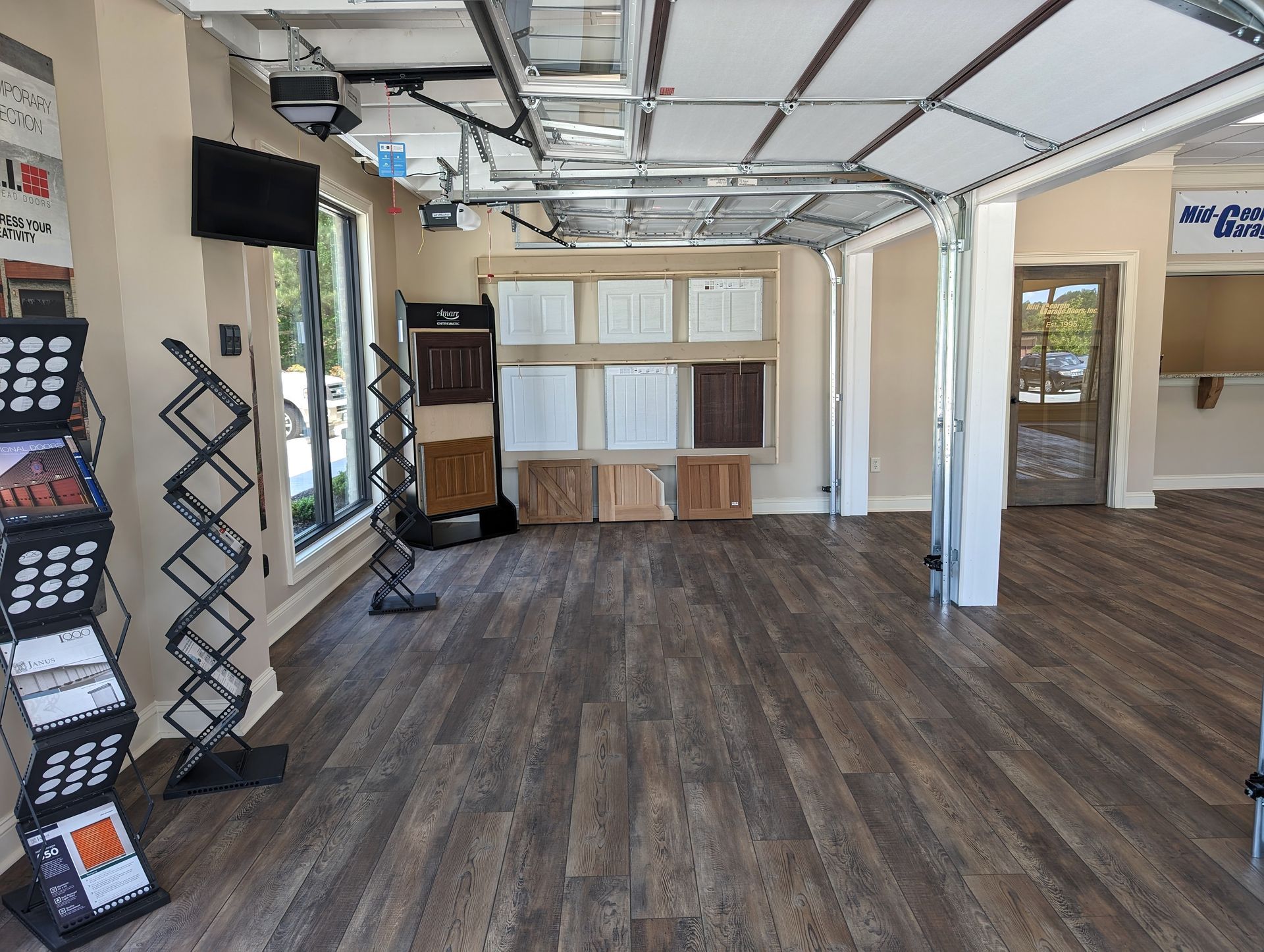 A large room with a wooden floor and a display of different types of garage doors.
