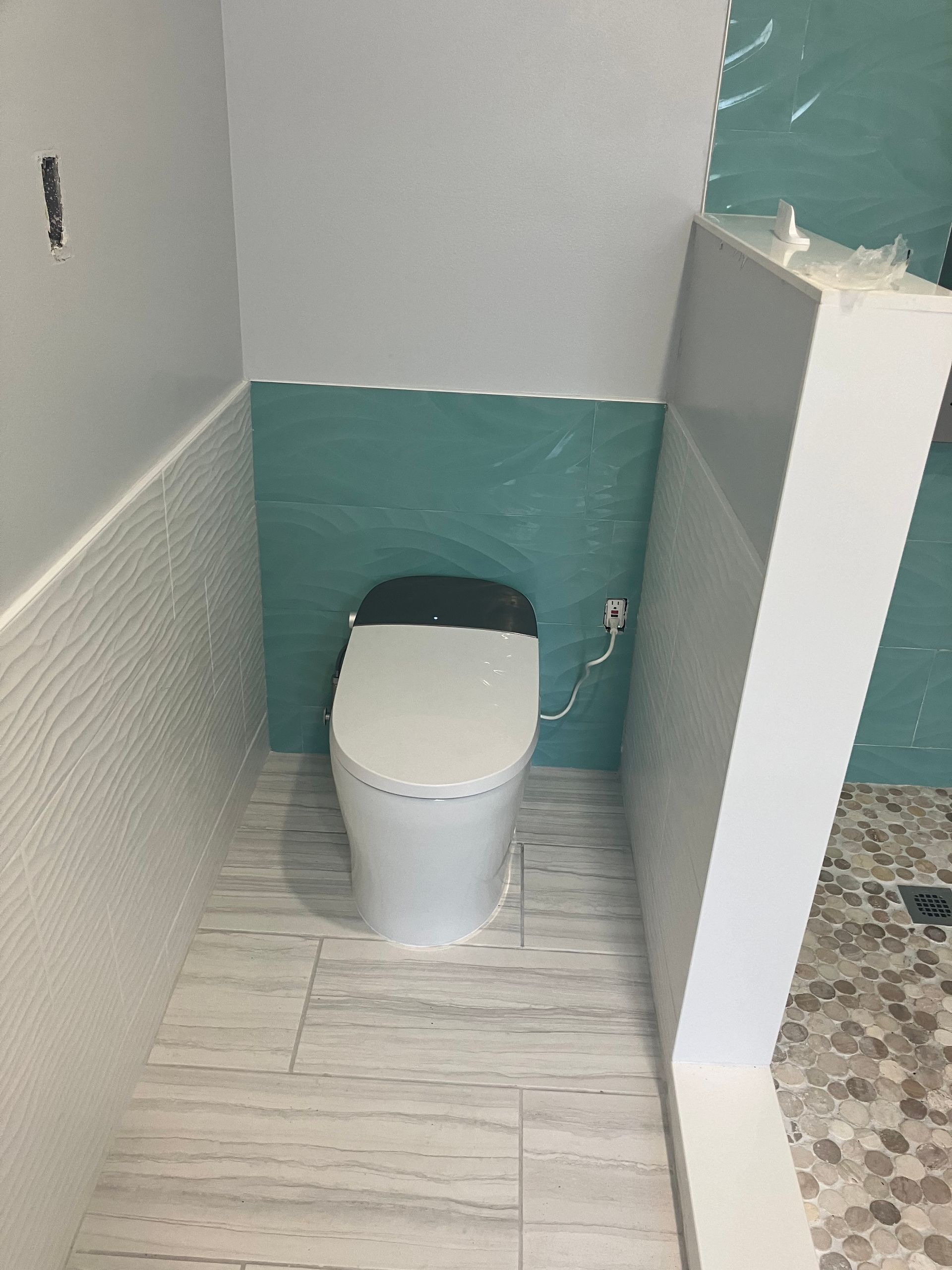 A man is fixing a shower head in a bathroom.