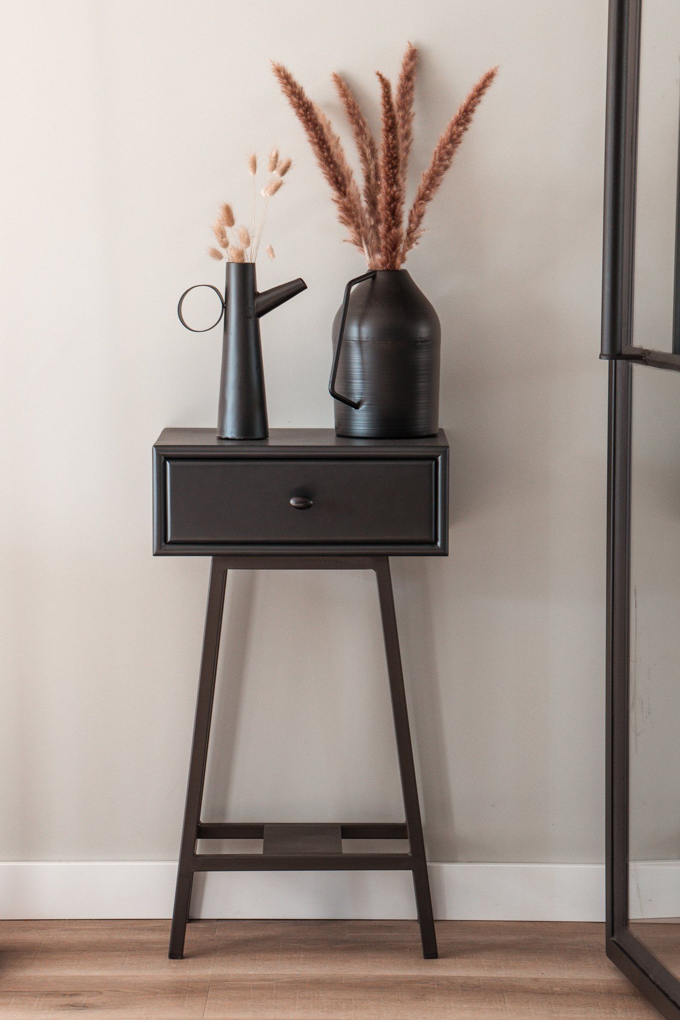 Een tafeltje met daarop een vaas met droogbloemen.