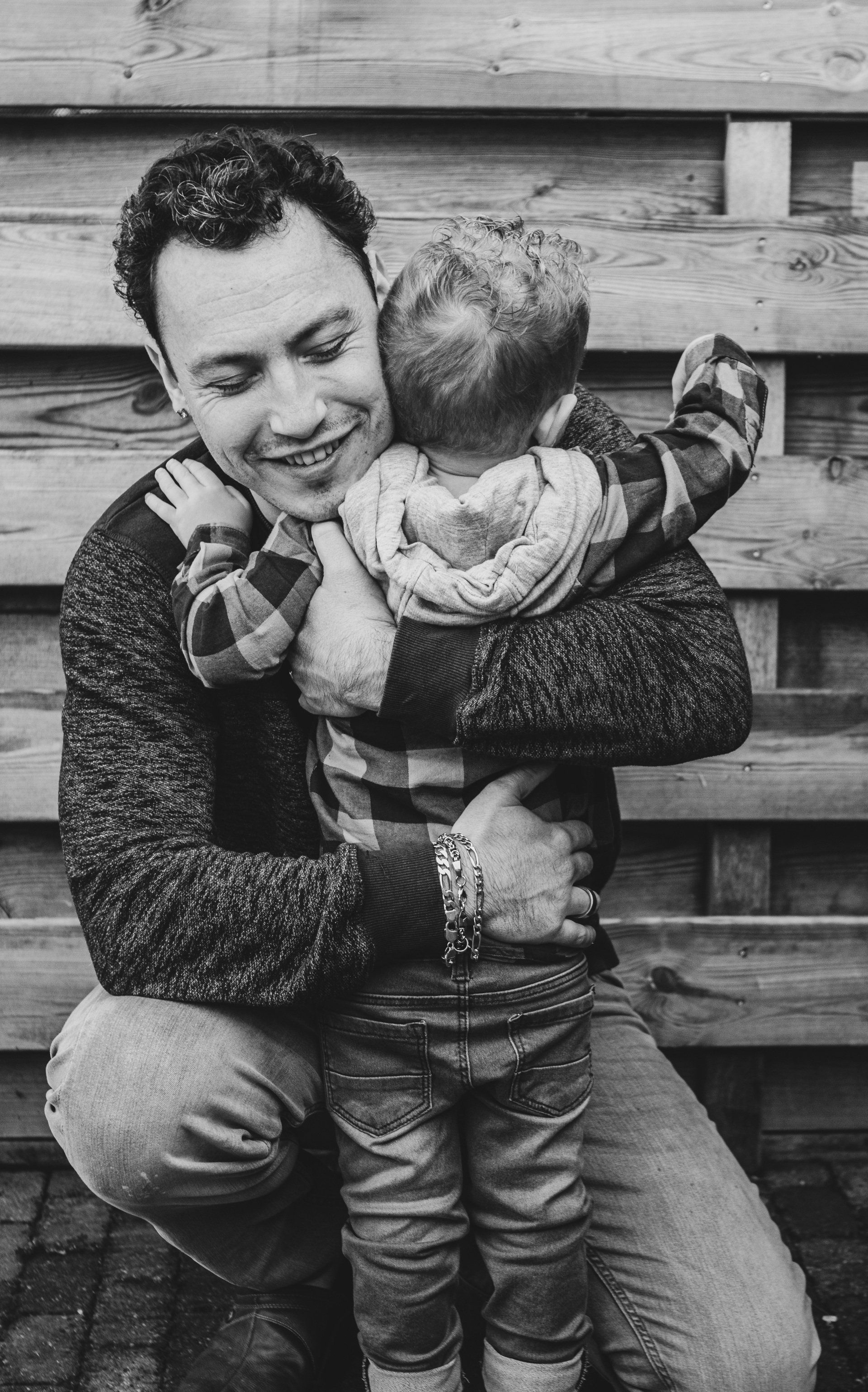 Een man houdt een baby in zijn armen op een zwart-witfoto.