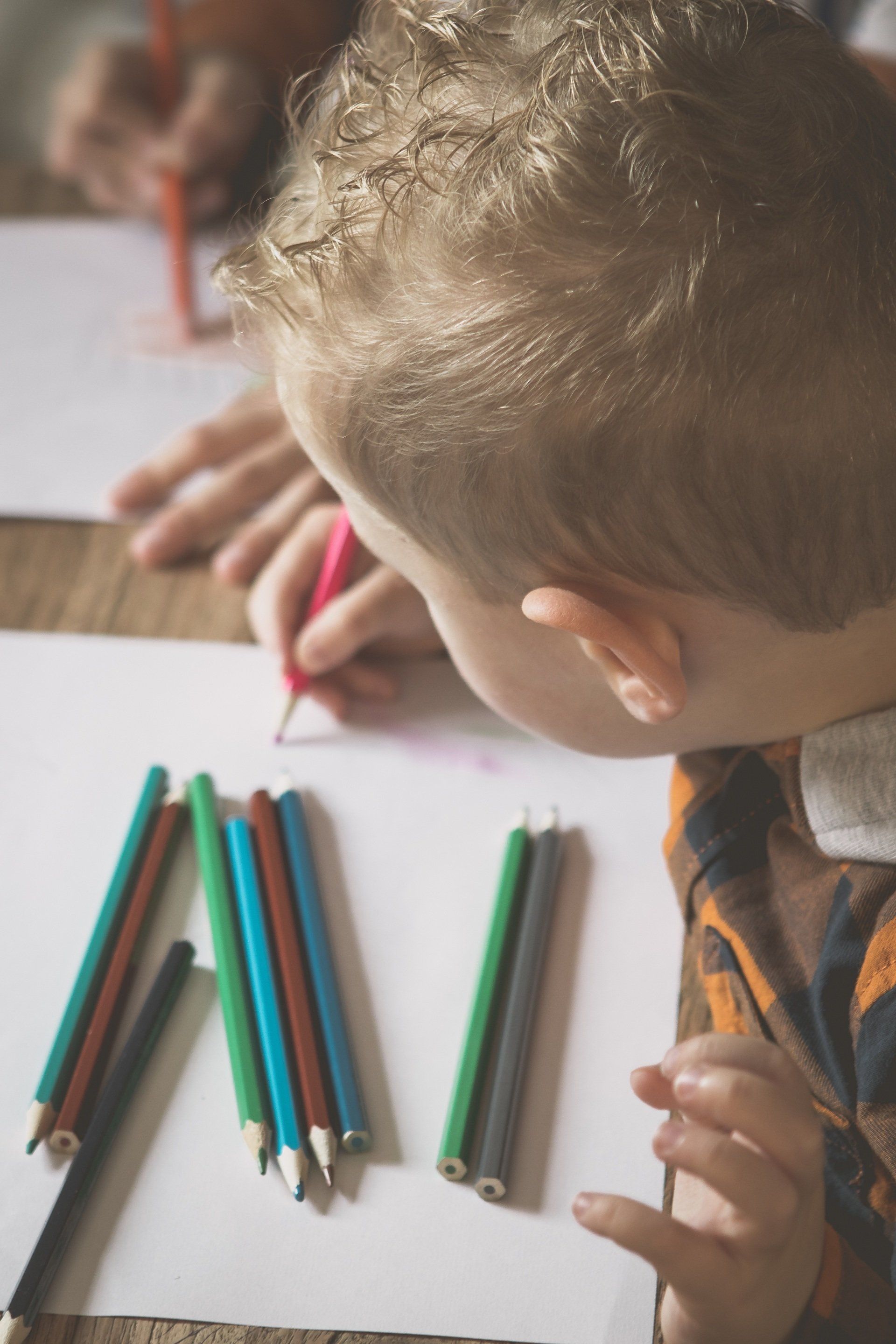 Een jonge jongen tekent met kleurpotloden op een vel papier.