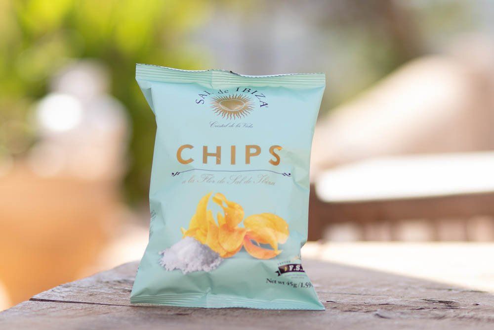 Op een houten tafel ligt een zak chips. Sal de Ibiza