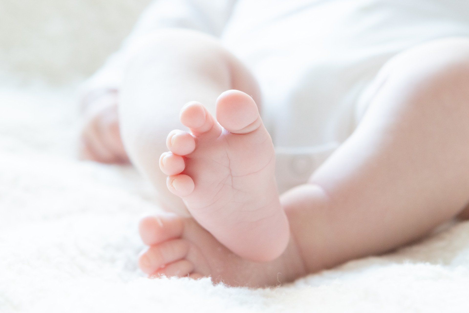 De voeten van een baby liggen op een witte deken.
