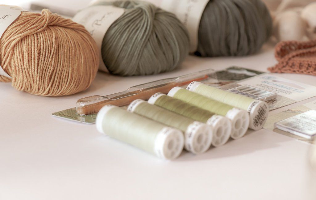 Een tafel met daarop bolletjes garen en klosjes draad.