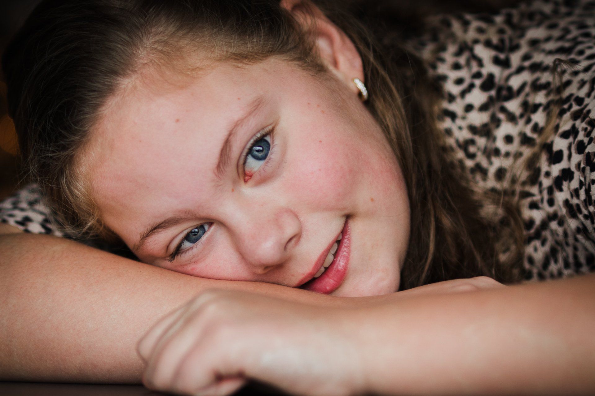 Een jong meisje ligt met haar hoofd op haar arm.