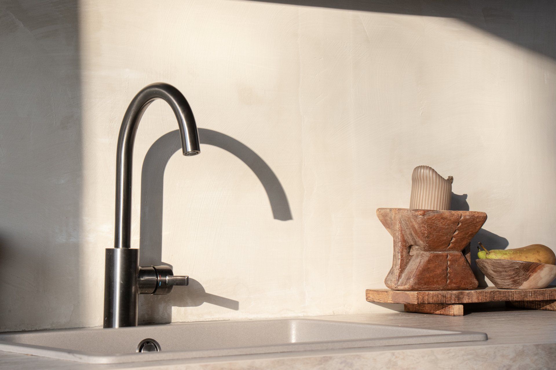 Een aanrecht met kraan en een dienblad met fruit op het aanrecht.