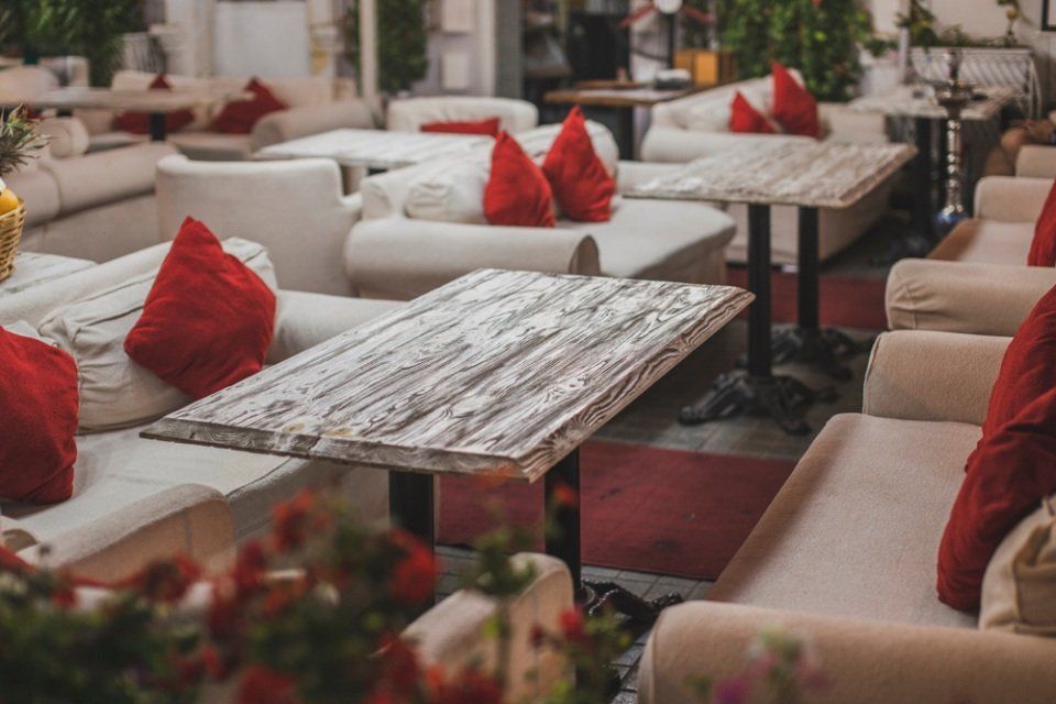 locale con tavoli in legno e divanetti