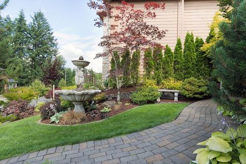 Stone path leads through a well-landscaped yard with a fountain, trees, and a bench.