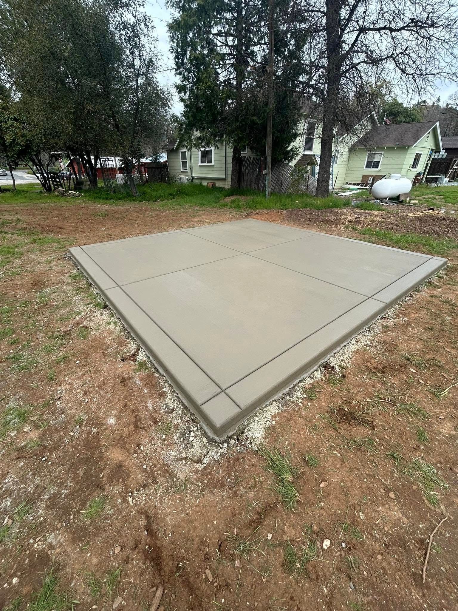 A concrete walkway leading to a house with a lush green lawn.