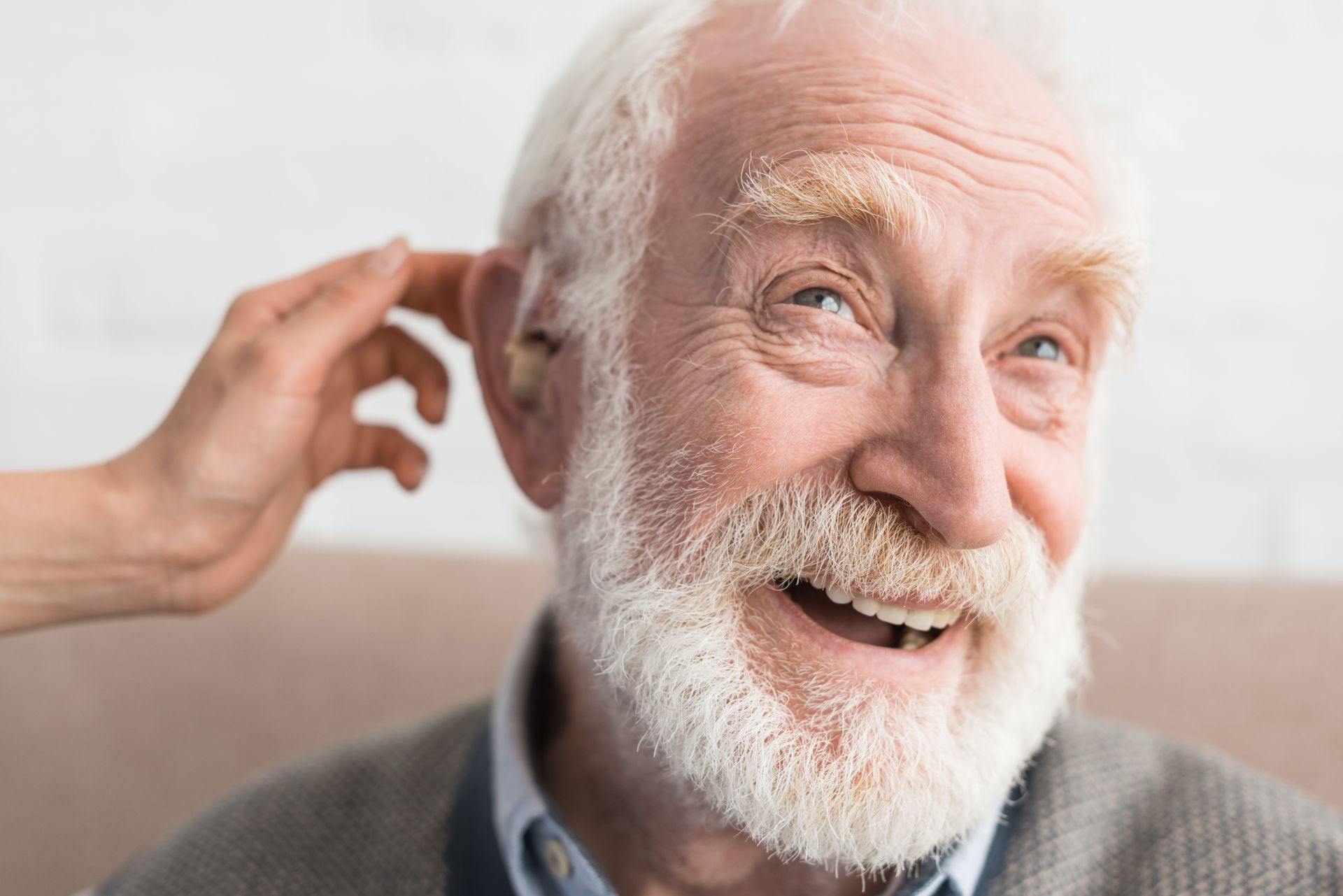 Fotografía de un hombre de la tercera edad feliz por volver a escuchar con un audífono para sordo debido a la hipoacusia