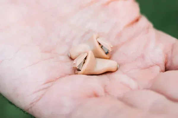 Fotografía de una mano de una persona mostrando algunos tipos de implantes auditivos