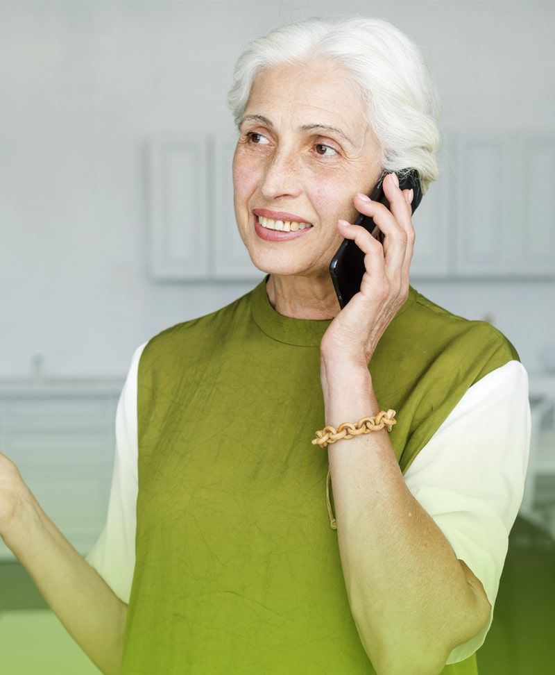 Una mujer con un chaleco verde está hablando por un teléfono celular.