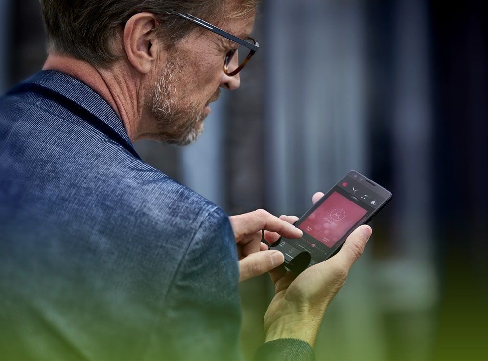 Un hombre que lleva gafas sostiene un teléfono móvil en la mano.