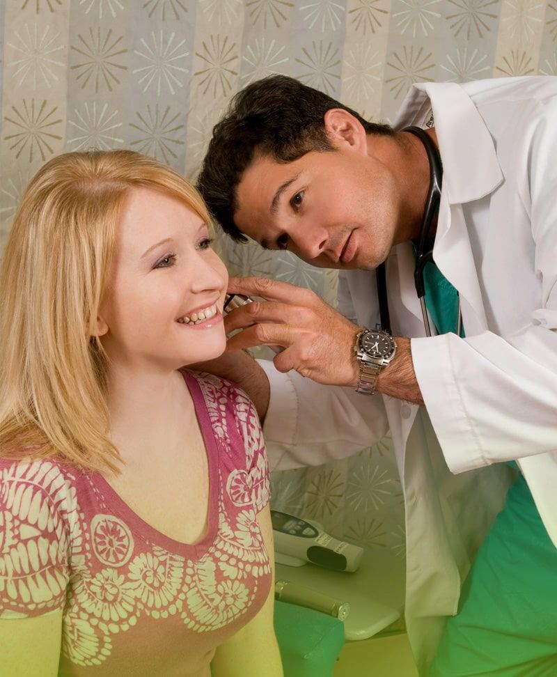 Un médico examina la oreja de una mujer con un estetoscopio.