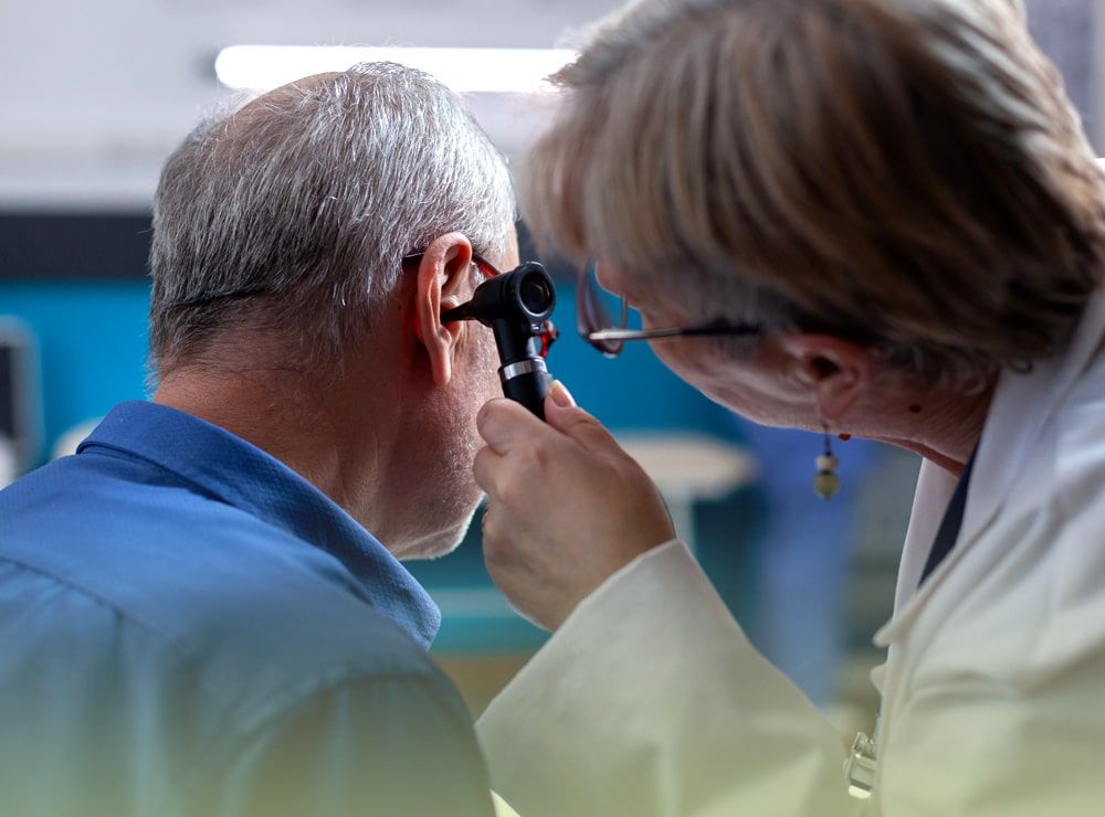 Un médico está examinando la oreja de un hombre con un otoscopio.