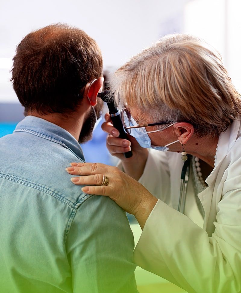 Un médico está examinando el oído de un hombre con un otoscopio.