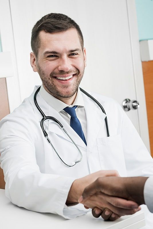 Un médico le estrecha la mano a un paciente en un hospital.