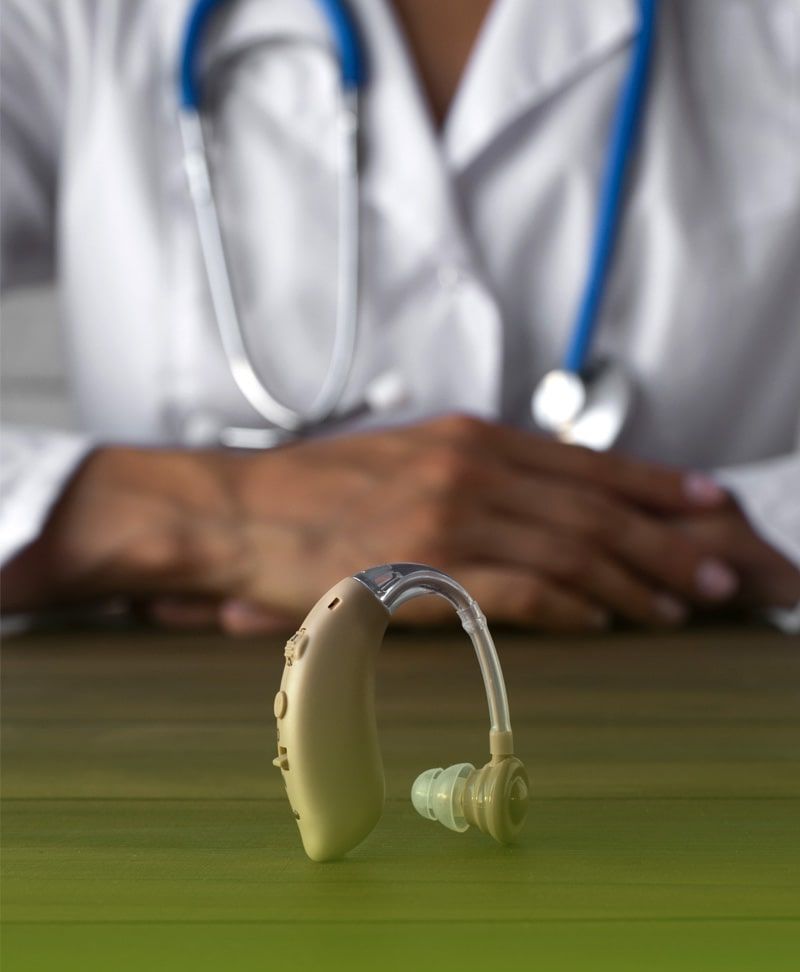 Un audífono está sobre una mesa frente a un médico.