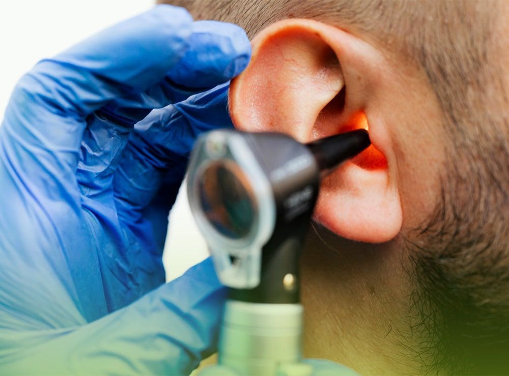 Un médico está examinando la oreja de un hombre con un otoscopio.