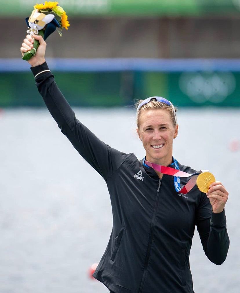 Emma Twigg holding her Olympic Gold Medal on the podium in Tokyo
