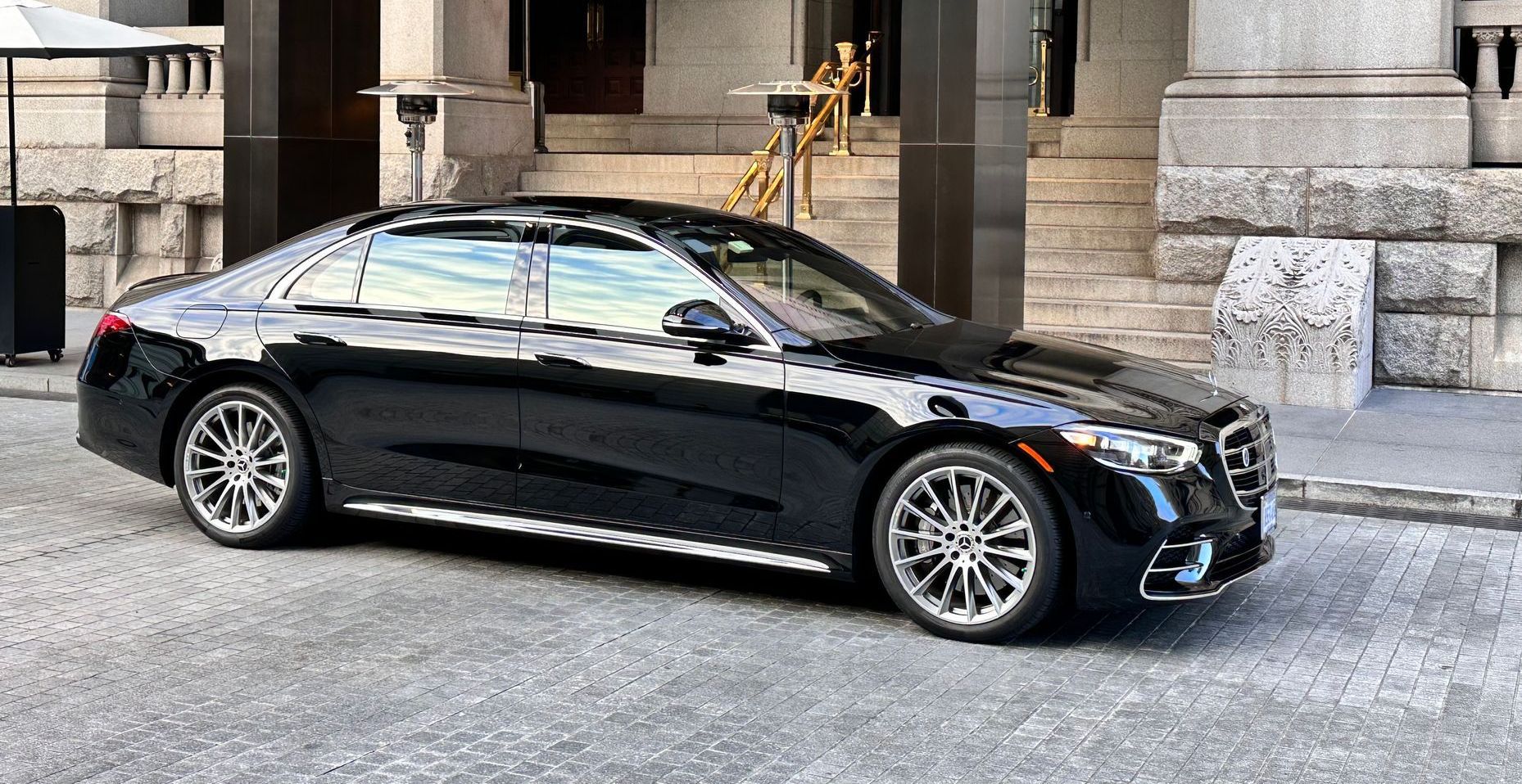 A black mercedes benz s class is parked in front of a building.