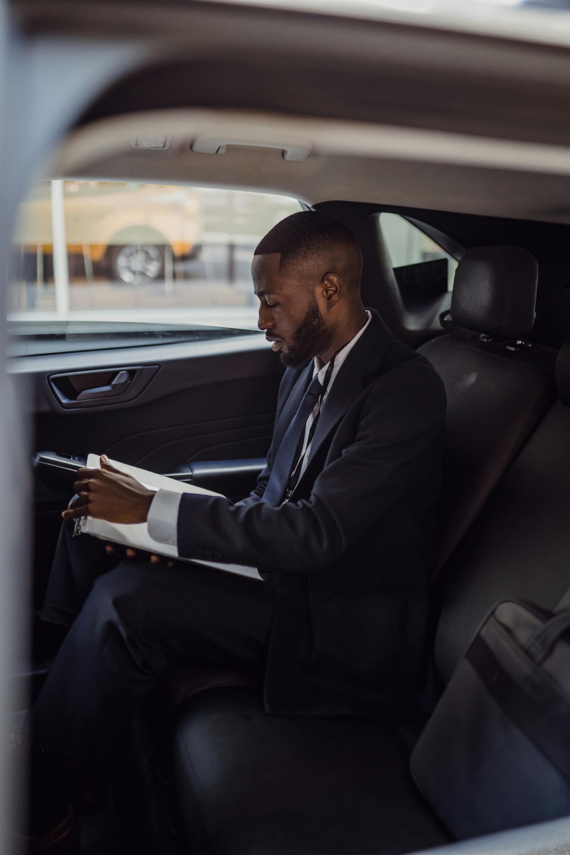 A man in a suit is sitting in the back seat of a car.