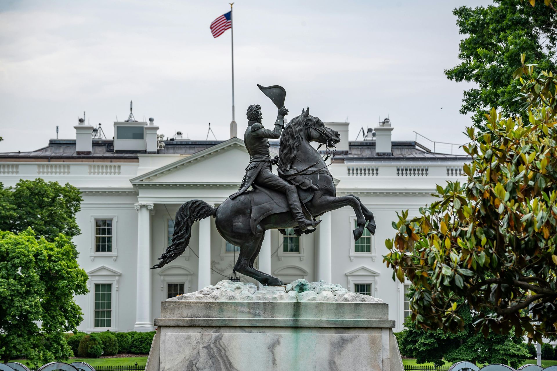 A statue of a man riding a horse in front of the white house.
