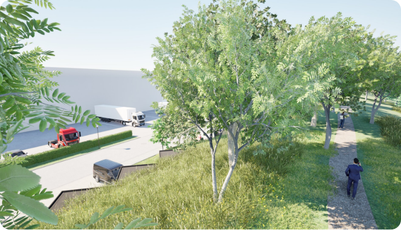 A paved path winds past a grassy hill and trees, bordering a commercial parking area with trucks near a warehouse wall.