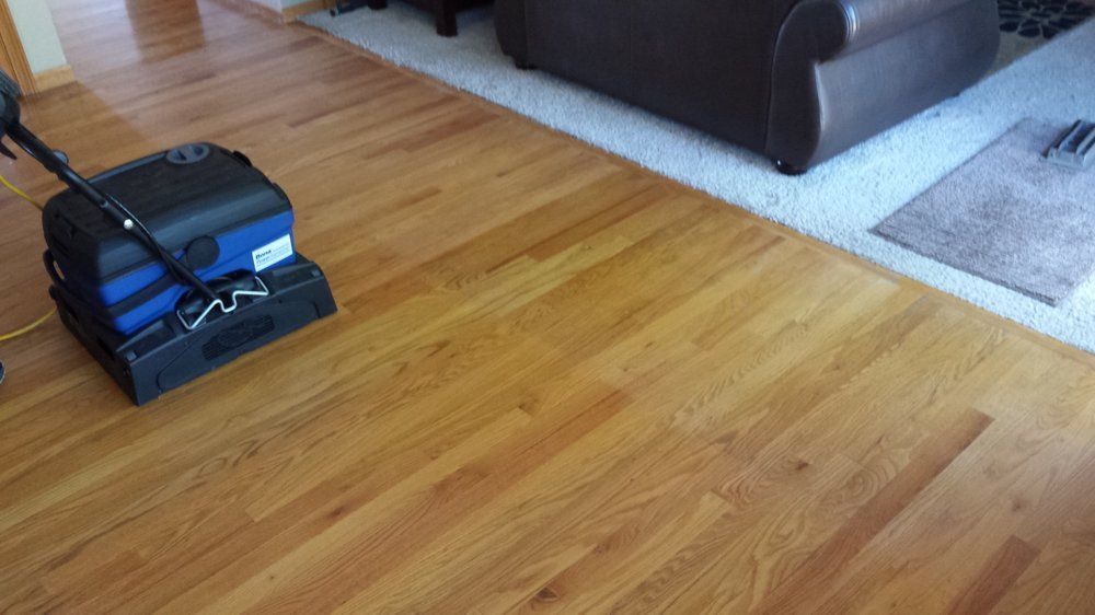 A vacuum cleaner is sitting on a wooden floor in a living room.