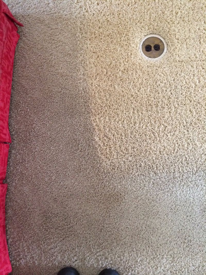 A person is standing on a dirty carpet next to a clean carpet.