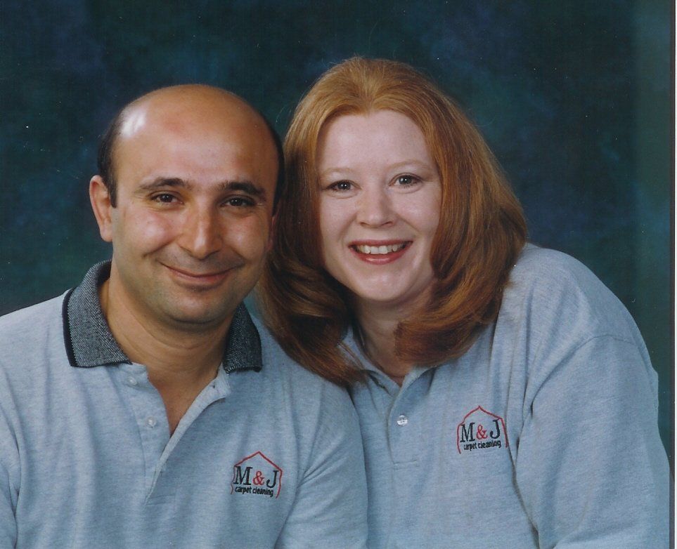 A man and a woman are posing for a picture and the man 's shirt says m & j