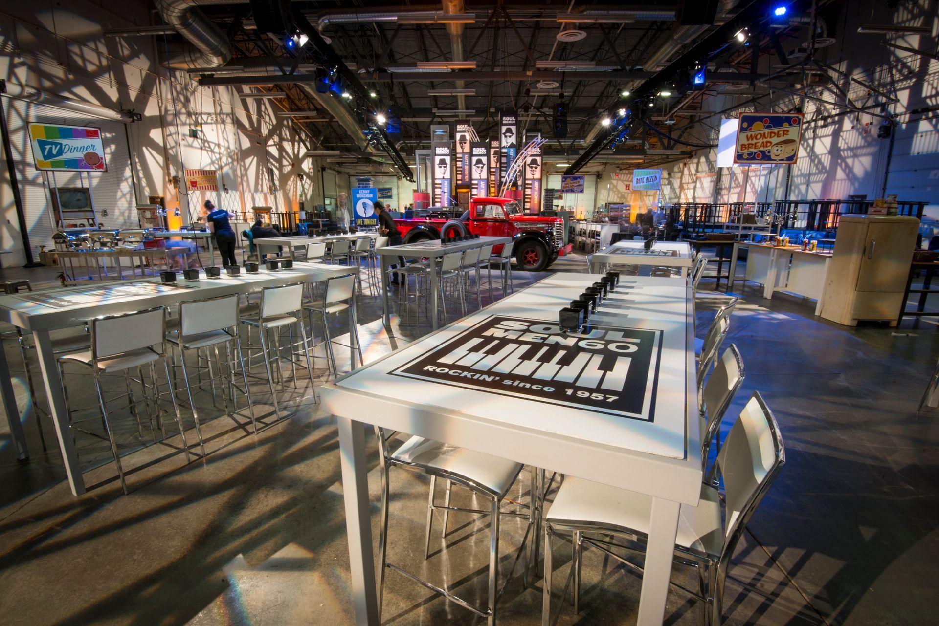 A large room with tables and chairs and a jeep on display.