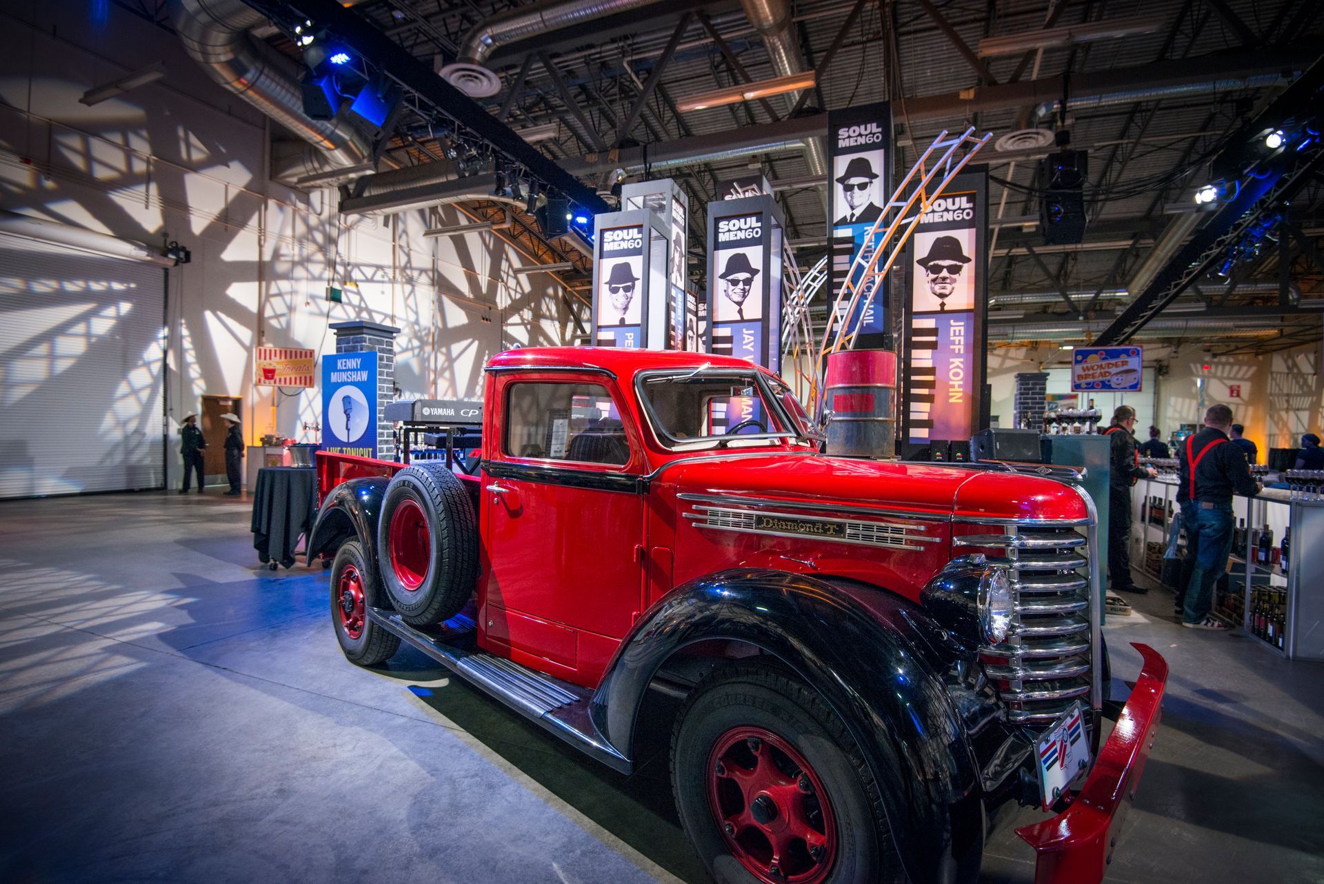 A red truck is parked in a large room at a car show.