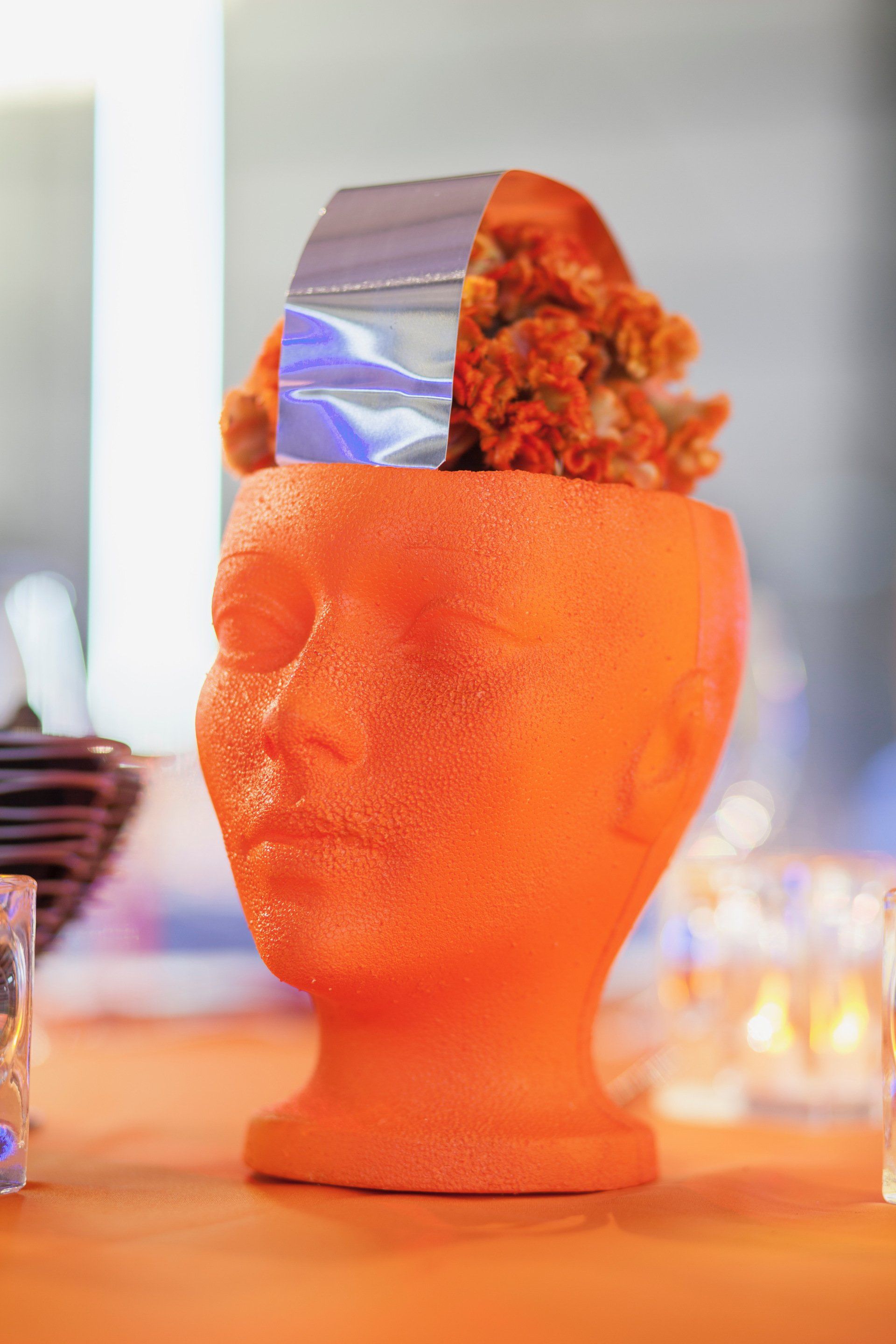 A styrofoam head with flowers in it is sitting on a table.