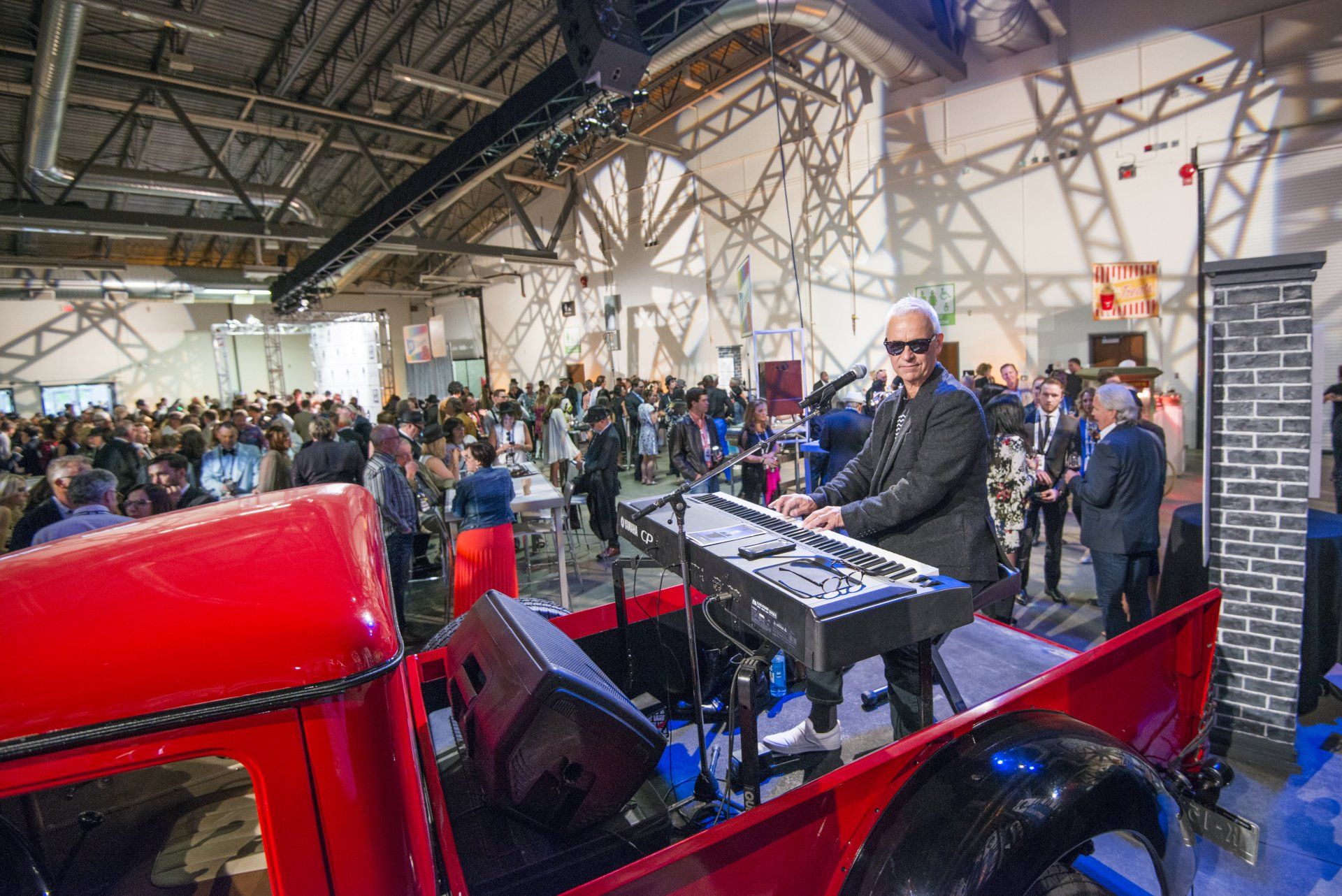 A man is playing a keyboard in the back of a red truck.