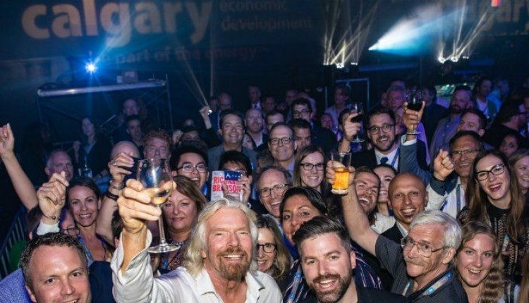 A man is holding a glass of wine in front of a crowd of people.