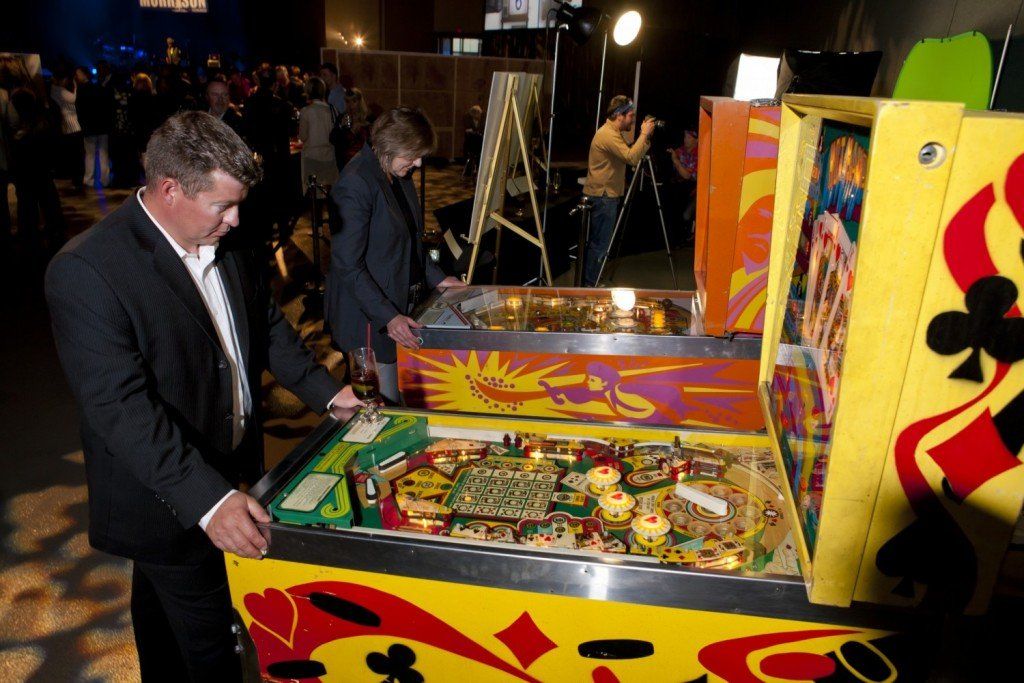 A man in a suit is playing a pinball machine