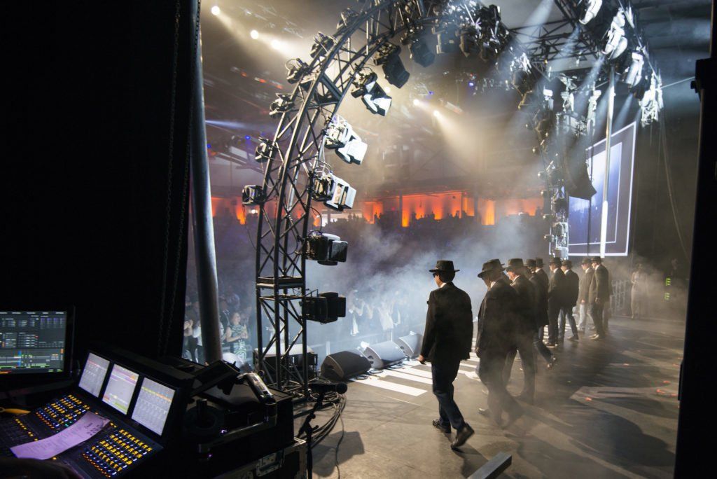 A group of people are standing on a stage in front of a large screen.