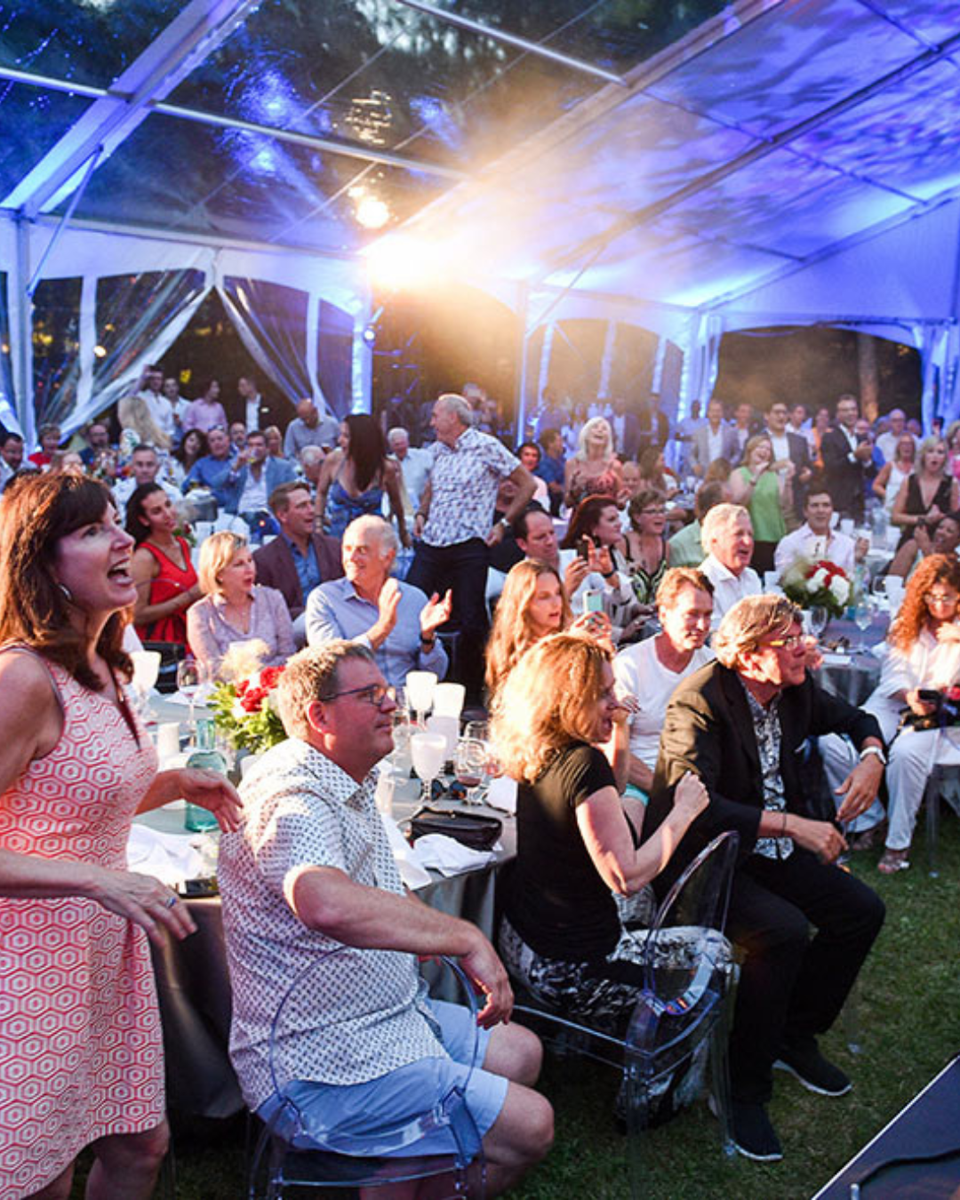A large group of people are sitting under a clear tent.