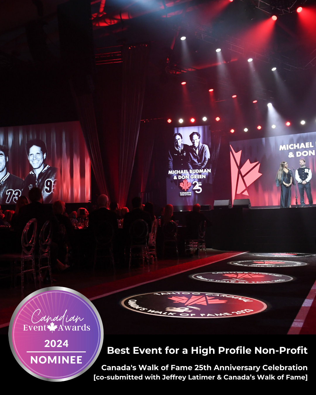 A group of people are standing on a stage in front of a large screen.