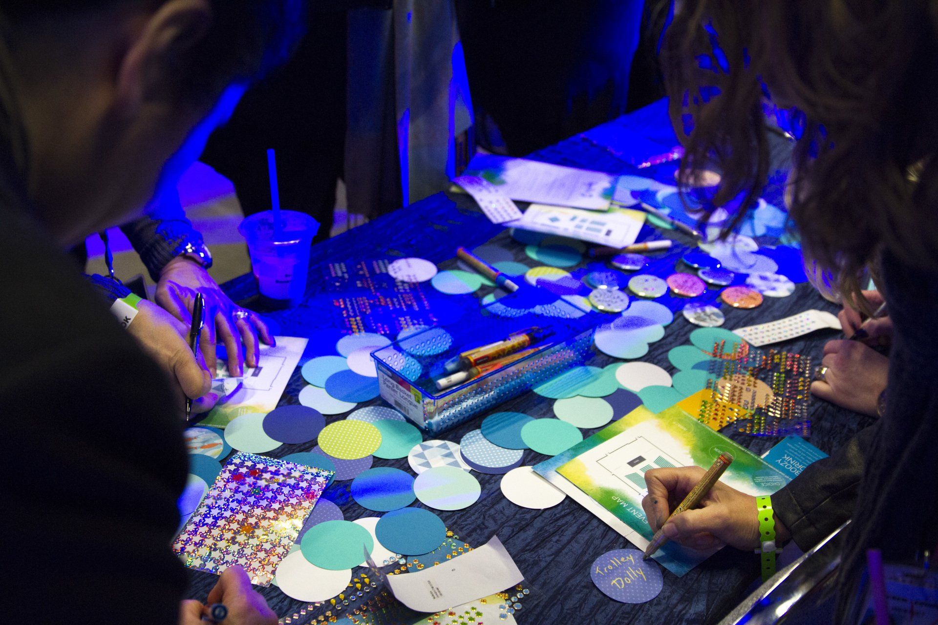 A group of people are sitting around a table drawing on paper